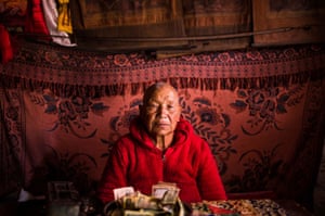 Travel category runner-up ‘Annapurna adventure’ a portrait of an elderly man dressed in red sitting in front of a draped red carpet
