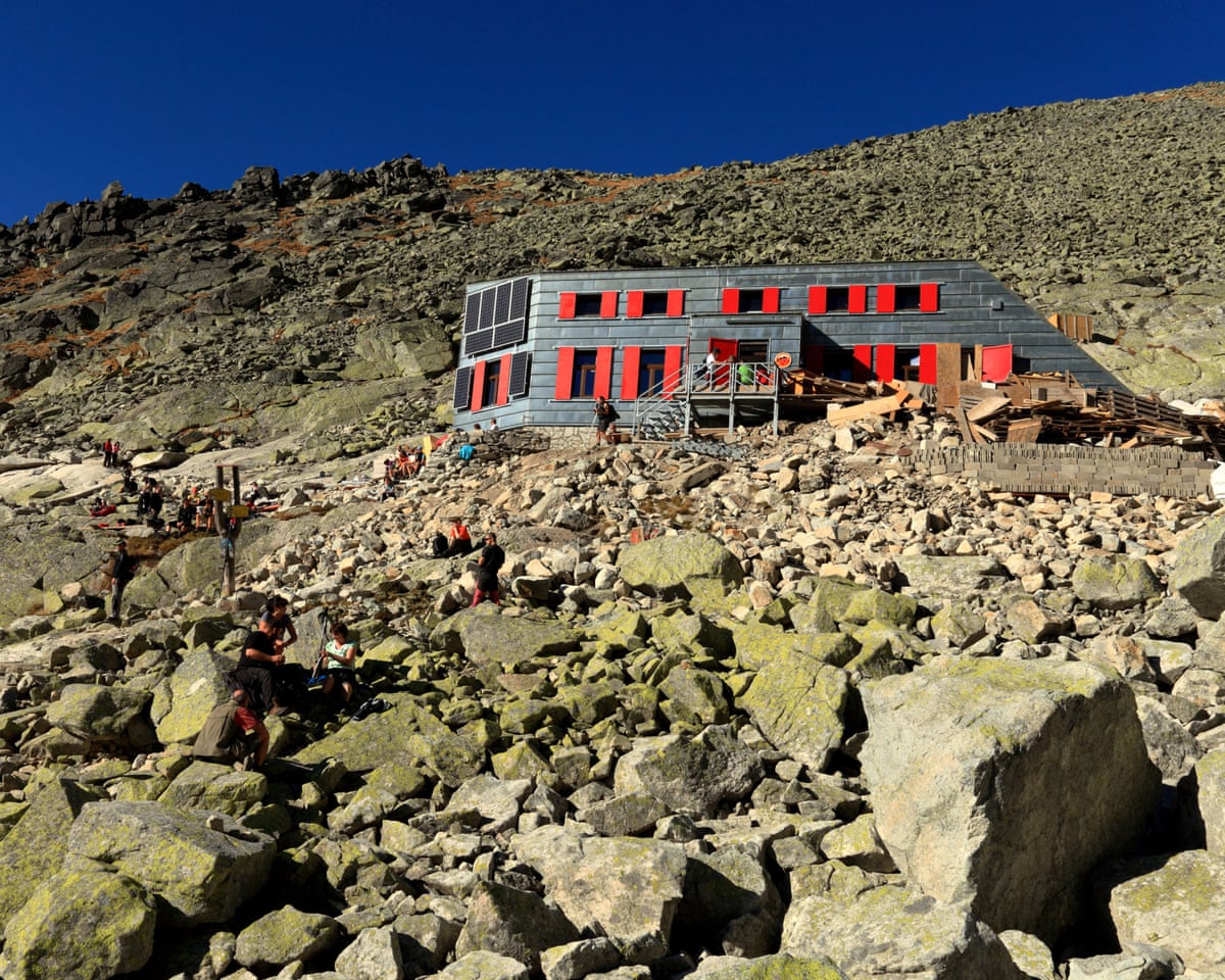 A hut with red windows on a rocky mountain side