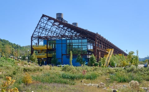 landscape showing the frame of a former steel mill converted to a hub for tech, robotics, and advanced manufactoring is surrounded by lush greenery