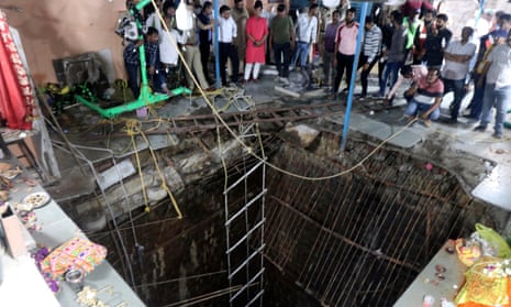 People stand around a structure built over an old temple well that collapsed on Thursday.