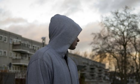 Teenager in hoodie outside block of flats