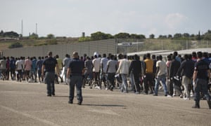 Italian border police with crowd of men