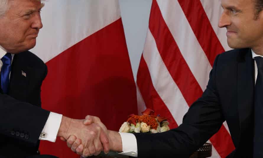 Emmanuel Macron gives Trump a knuckle-crushing handshake.