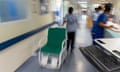 NHS hospital. Nurse pulls a wheelchair down a corridor
