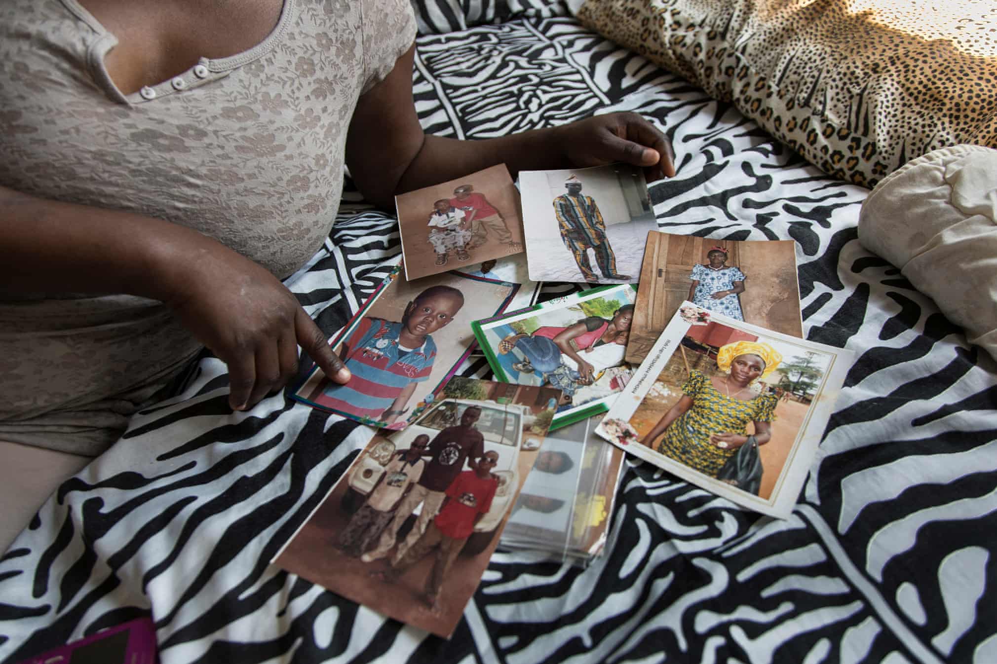 A woman displays photos of relatives from Nigeria.