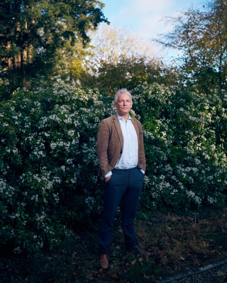 Portrait of Danny Kruger photographed outside, in front of a bush that is in flower