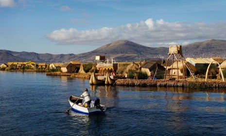 An Andean man rows a boat next to the shores of Uros islands at Lake Titicaca 