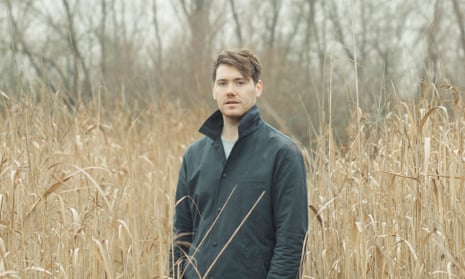 Joel Golby standing in a field of tall, pale corn or grass in winter