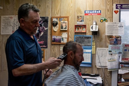 A man giving another man a haircut with a buzzer