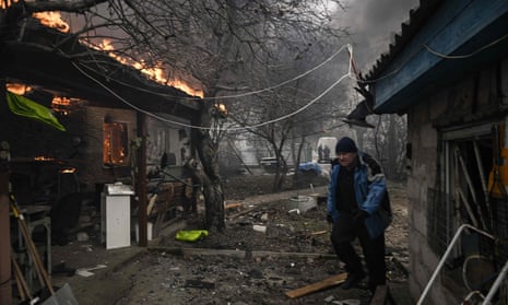 A man walks next to a burning house after being shelled in the city of Irpin, outside Kyiv.