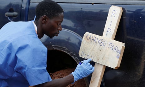 A Congolese Red Cross worker writes on a cross the name of Kahambu Tulirwaho, who died of Ebola, before a burial service at a cemetery in Butembo