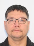 man in glasses looks ahead in booking photo