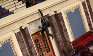 A protester is seen hanging from the balcony in the Senate Chamber in Washington, DC.