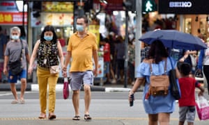 People cross a road in Singapore as the city state detected its first locally transmitted case of the Omicron variant, warning more cases are likely.