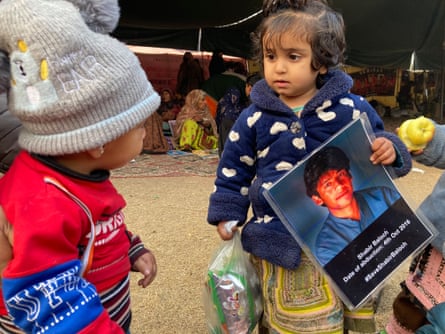 Three-year-old Shari holds a poster of her uncle.