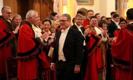 Starmer, centre, with people around, some applauding in formal wear