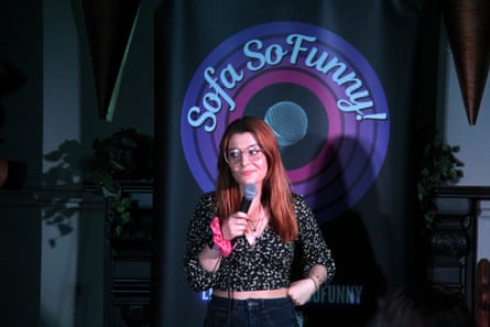 Cashman on stage with a mic and a backdrop reading ‘Sofa So Funny’