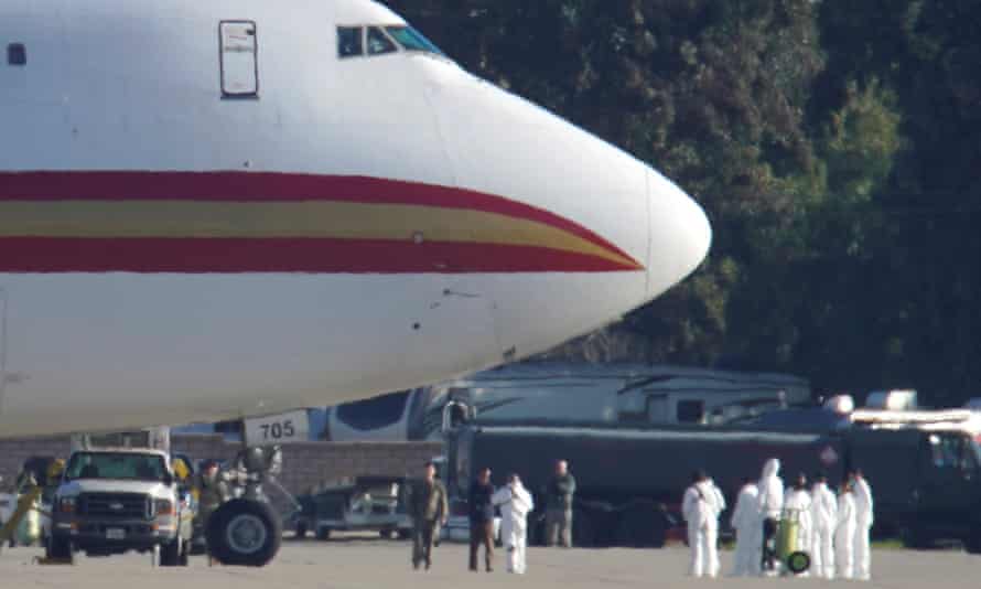 Personnel in protective clothing approach an aircraft repatriating Americans from Wuhan after it landed at March Air Reserve Base in Riverside County, California