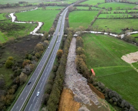 A huge pile of waste next to a dual carriageway near a river