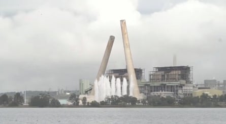 Two chimneys collapse in the skyline in front of a power station
