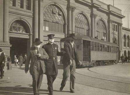 A police officer wearing a flu mask leads two men away from the Ferry building in San Francisco in 1918.