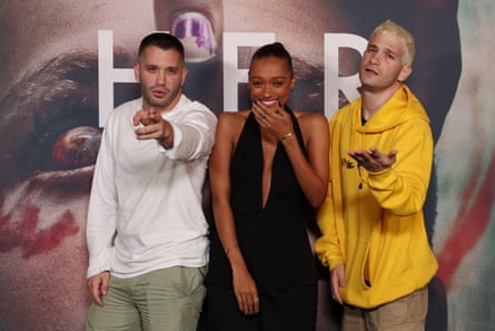 Michael Philippou, Sophie Wilde and Danny Philippou stand on the red carpet with a poster for Bring Her Back behind them. The brothers and mugging for the camera, she is laughing