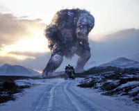 Movie still showing the troll Jötunn towering over a vehicle on a snowy road