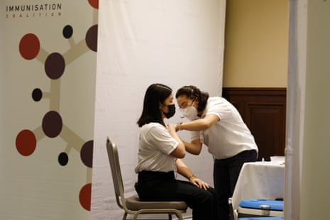 A woman receives a free flu vaccination, next to a banner saying Immunisation Coalition
