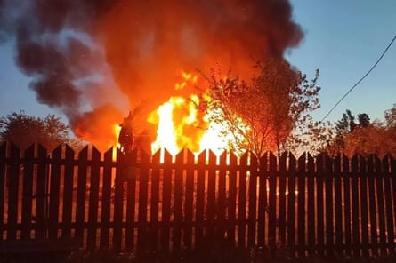 A burning building seen through a fence.
