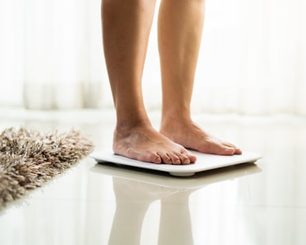 Young woman standing on digital weight scale