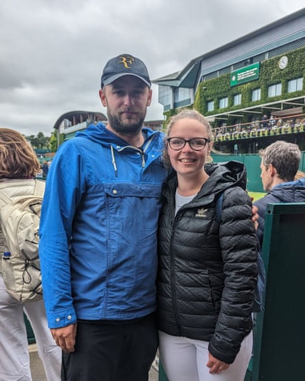 Man and woman stand with Wimbledon clock in background
