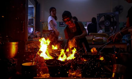 70-year-old chef Jay Fai (C) cooks on coal powered stoves at her Michelin star restaurant in Bangkok,