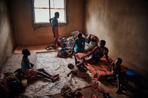 Women and girls sit on mattresses