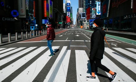 People wear face masks as they cross a street in Times Square in New York City.