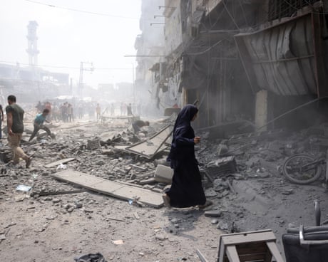 A Palestinian woman walks in the rubble after an Israeli strike on Gaza City's southern al-Zeitoun neighbourhood on Thursday.