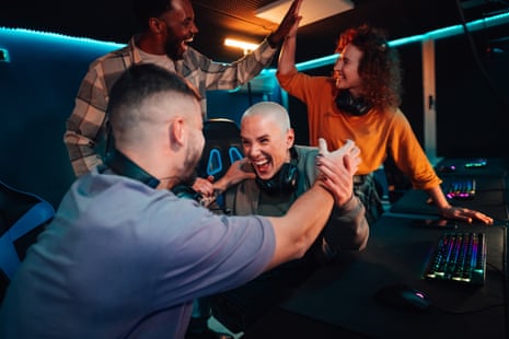 Friends and gamers cheering and high‑fiving after winning a video‑game competition indoors at a gaming café