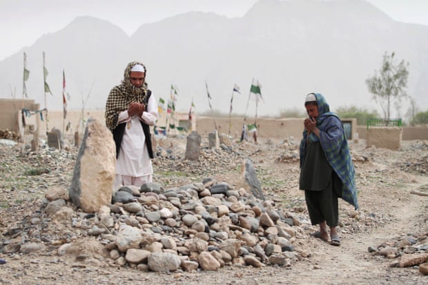 Afghan villagers pray over the grave of one of the sixteen victims killed in a shooting rampage by Robert Bales.