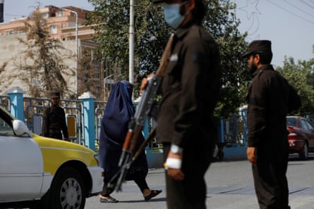 An Afghan woman walks among Taliban soldiers at a checkpoint in Mazar-i-Sharif.