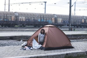 A girl looks out from her tent set up near the Idomeni train station as she and her family wait to be allowed to cross the border into Macedonia
