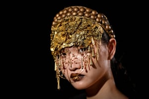 A model wearing an elaborate gold headdress which almost covers her face