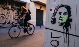A cyclist passes graffiti depicting mayor Ada Colau in the Gràcia neighbourhood of Barcelona.