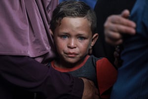 Close-up of a child crying with adults in the background