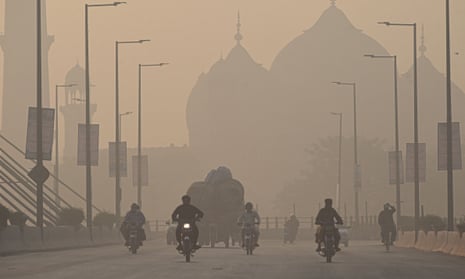 Commuters ride along a road amid smoggy conditions in Lahore on 16 November, 2021.