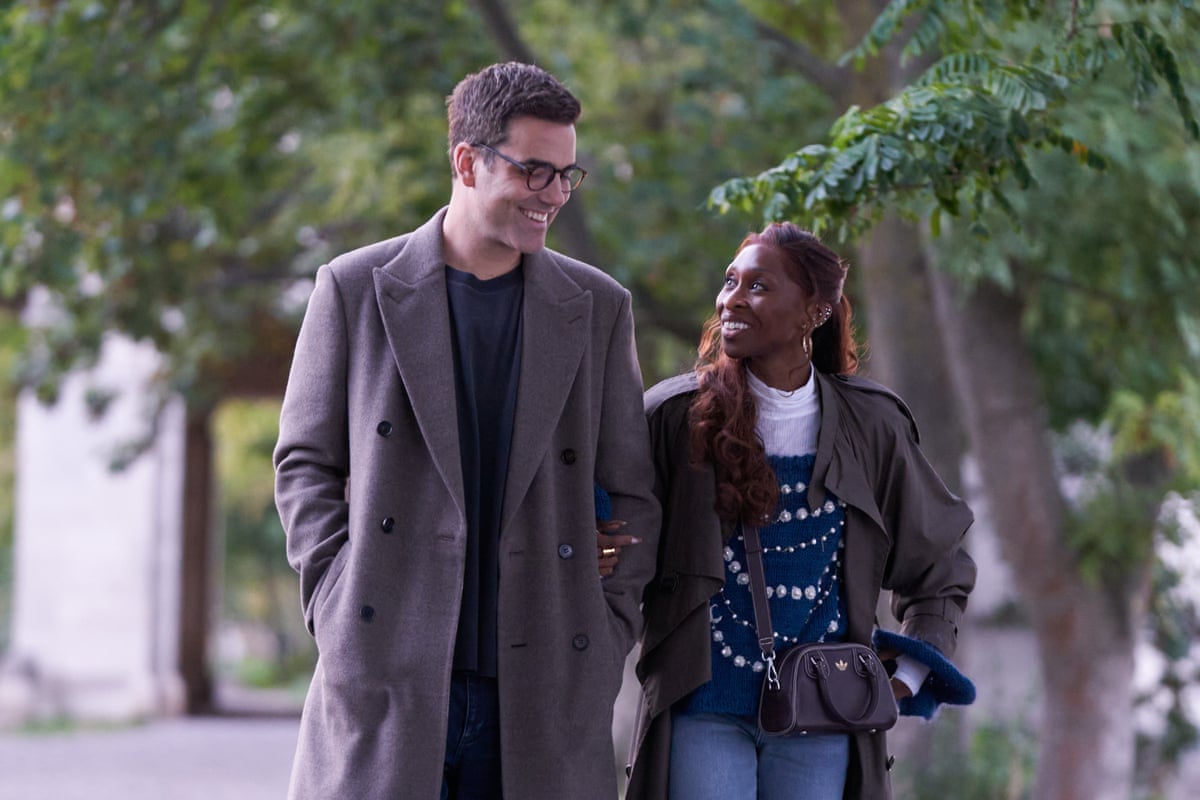 Daniel Ings and Cynthia Erivo walking down a street smiling at each other