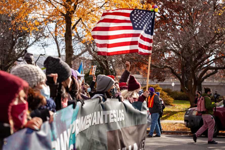 people march behind banner and carry US flag