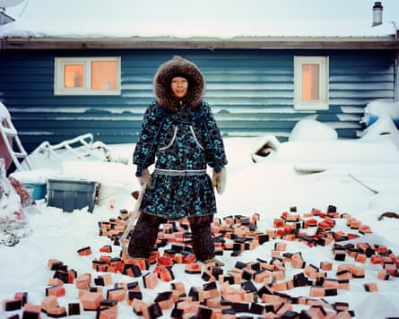 A woman in Indigenous winter clothing standing over a pile of chopped up whale blubber