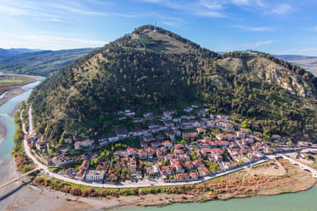 Aerial shot of a coastal hill town with red roofs in sunshine