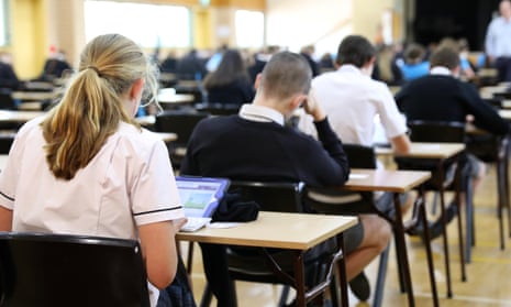 anonymous students in uniform sitting an exam online using digital tablets. Examination room set up with tables and desks in a high school hall.WT6CC0 anonymous students in uniform sitting an exam online using digital tablets. Examination room set up with tables and desks in a high school hall.