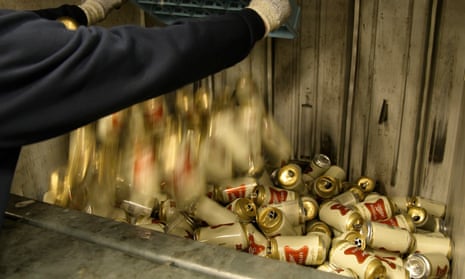 A worker dumps empty cans of Miller High Life beer into a machine to be crushed at the Westlandia plant in Ypres, Belgium.