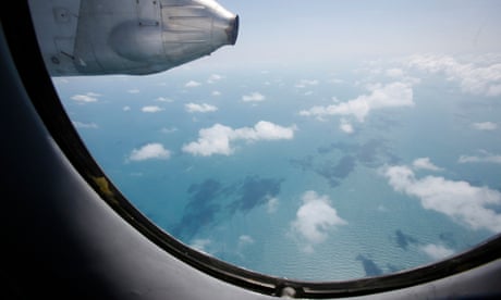 Clouds hover outside the window of an aircraft on a mission to find the missing Malaysia Airlines flight MH370